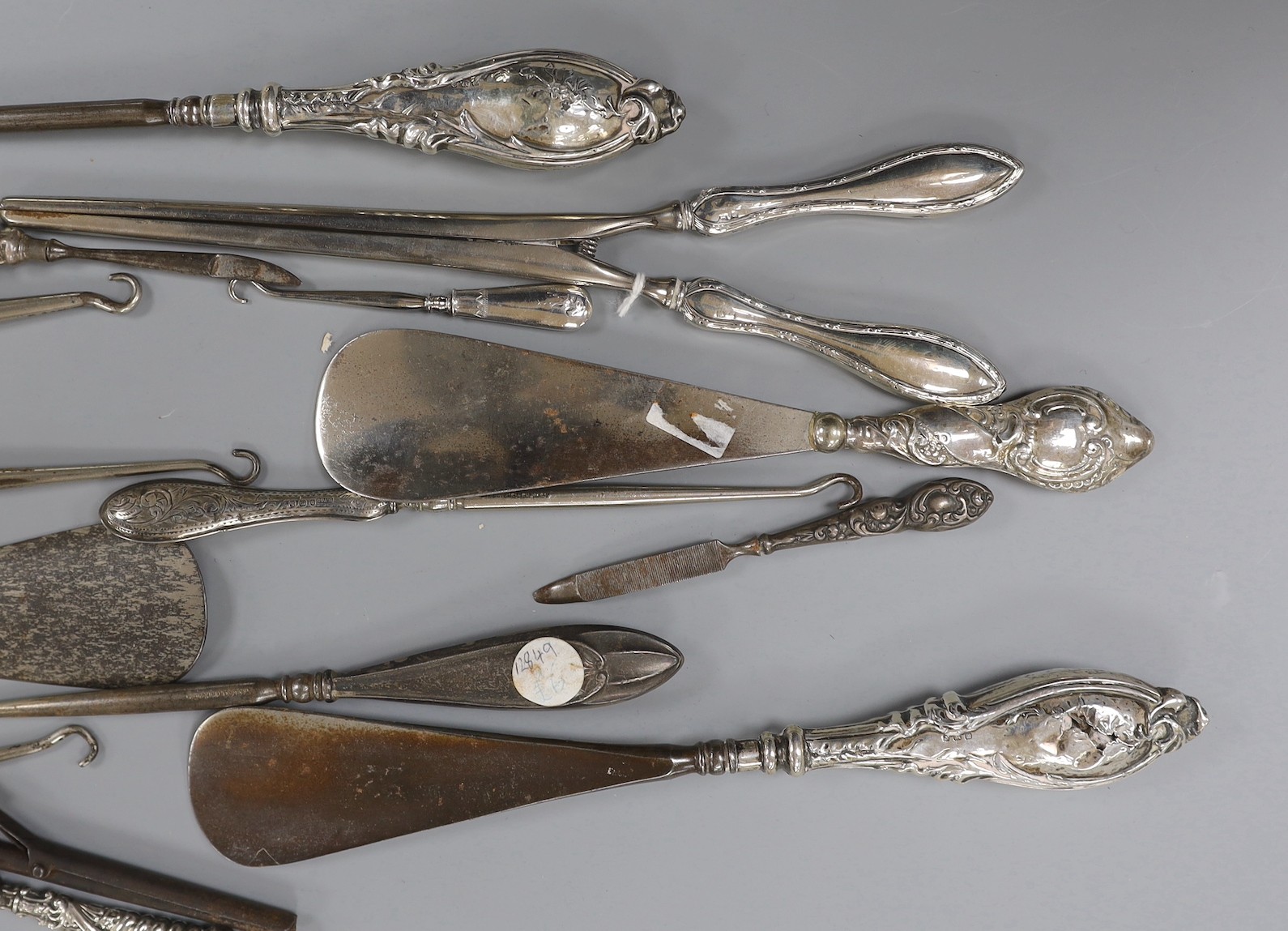 Four repousse silver handled shoe horns, seven similar button hooks, three nail implements, a pair glove stretchers and small pair of curling tongs.